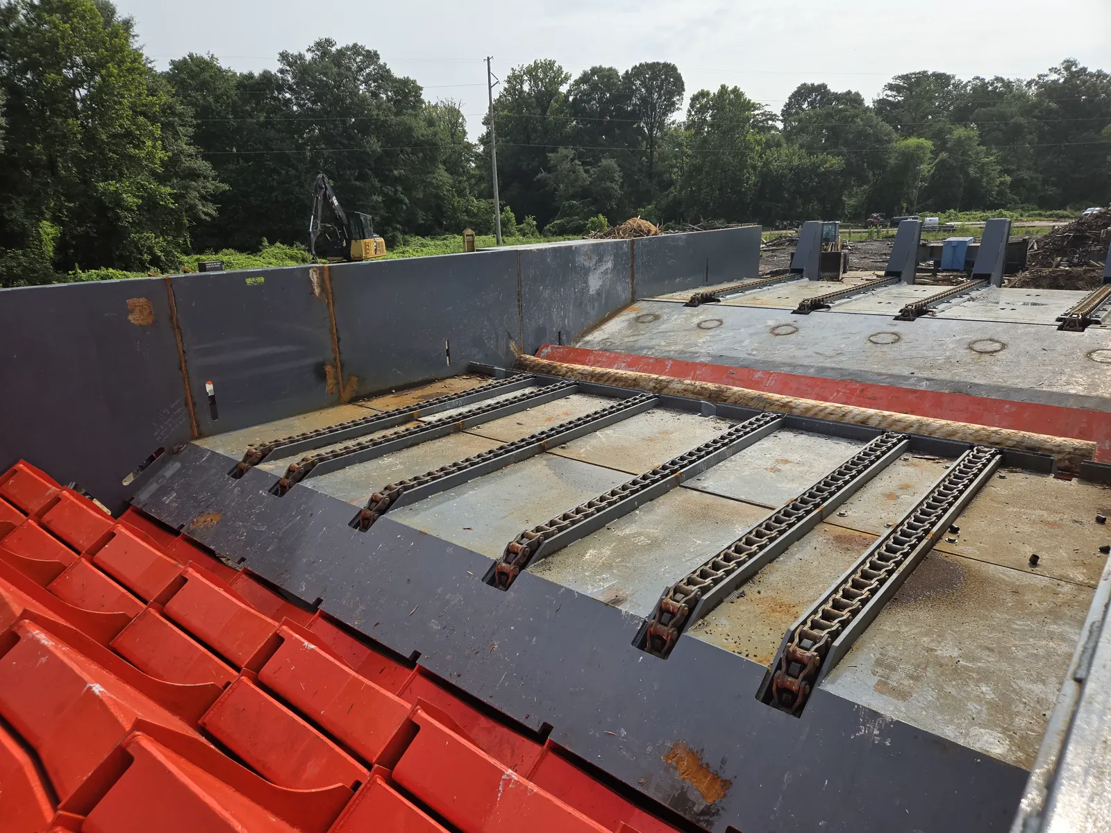 Chain-strand infeed deck feeding the step feeder, with plated pocket pusher flights in the foreground