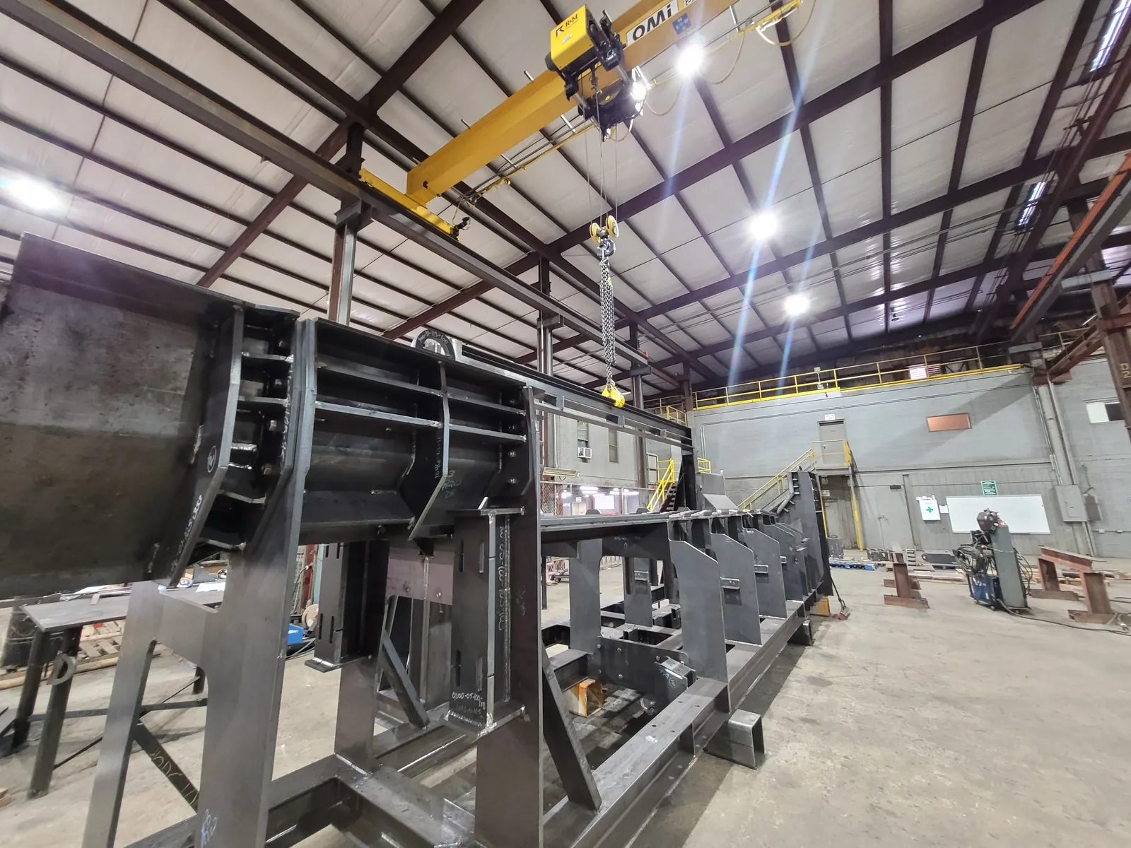 Heavy conveyor frame supported on stands beneath the OMI bridge crane