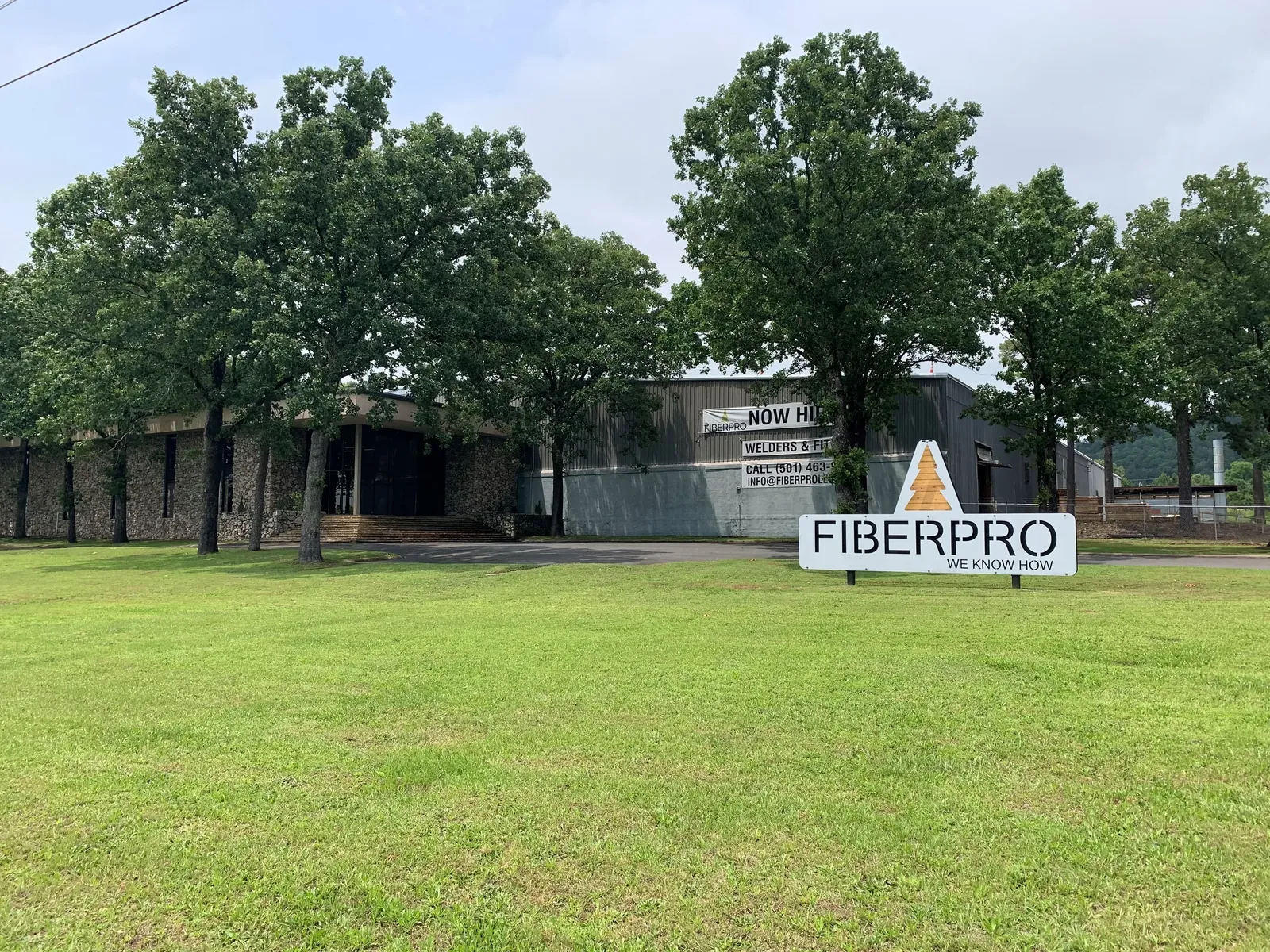 The FiberPro plant in Hot Springs, Arkansas — stone-front office among the oaks with the FIBERPRO monument sign at the road